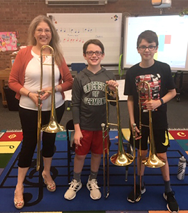 Two students and a staff member pose with instruments